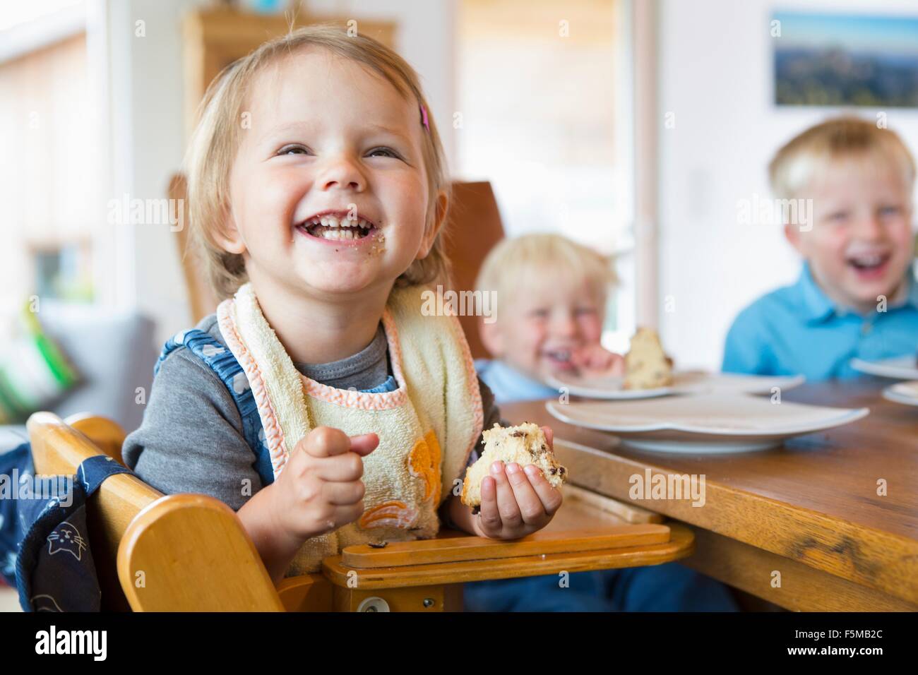 Trois jeunes enfants de manger du gâteau à table de thé Banque D'Images