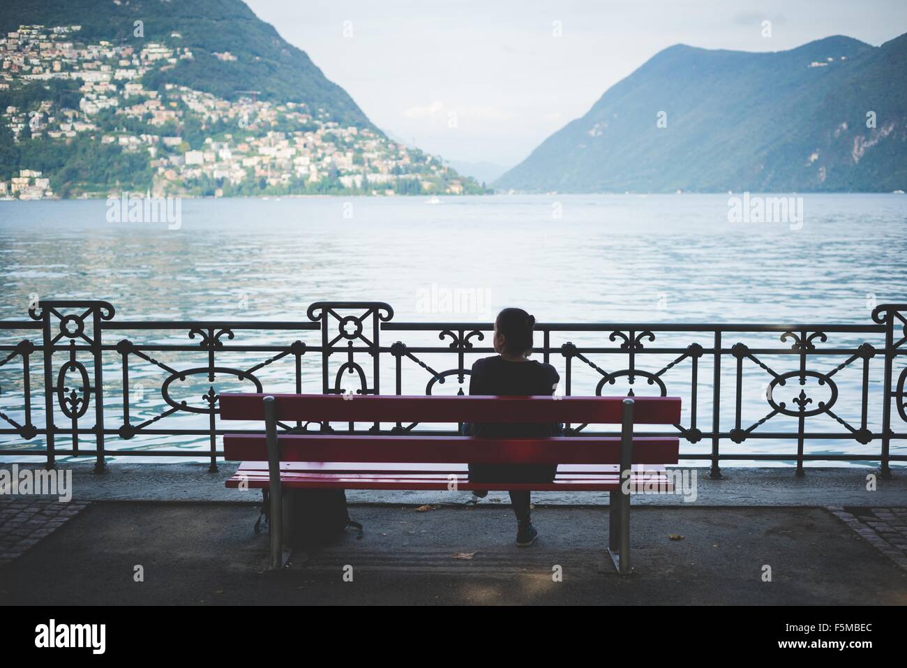 Vue arrière de la silhouette femme sur banc de parc avec vue sur le lac de Lugano, Suisse Banque D'Images