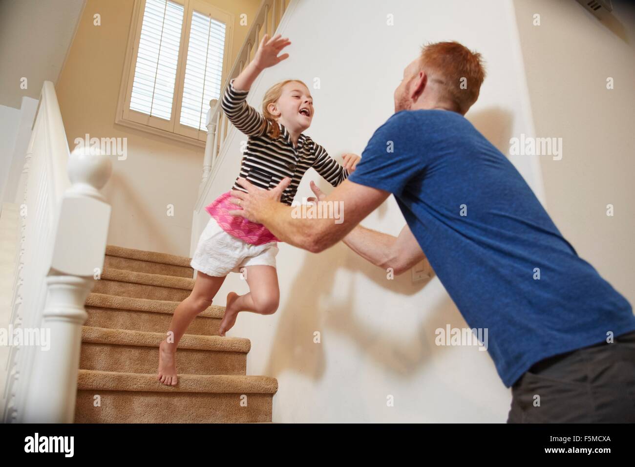 Jeune fille saute dans les bras du père sur l'escalier à la maison Banque D'Images