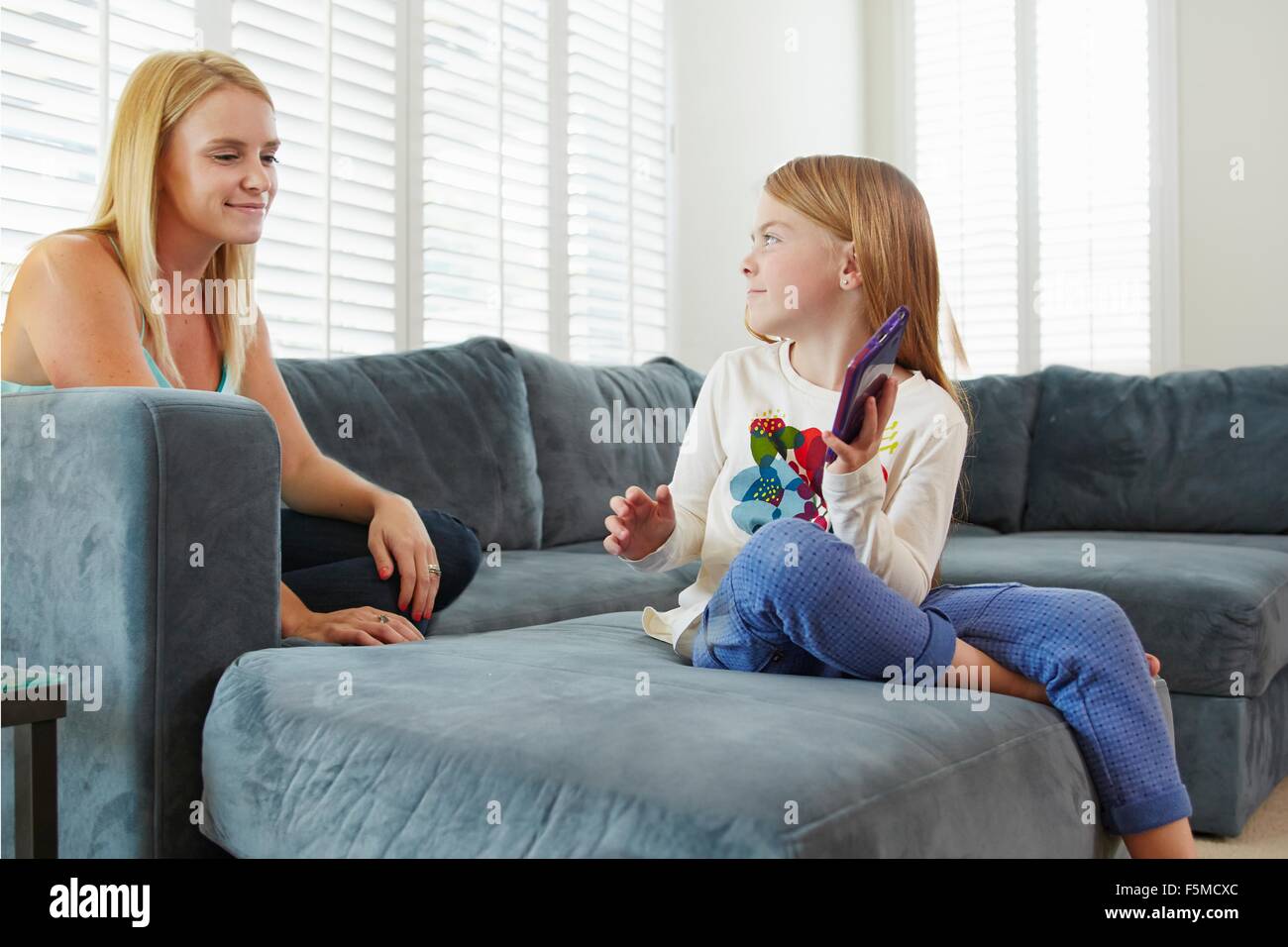 Mère et fille using digital tablet on sofa in living room Banque D'Images