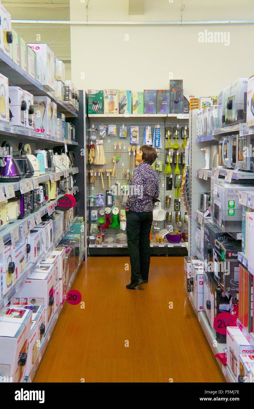 Femme d'âge moyen des achats dans un hypermarché dans le four à l'allée à la recherche d'une bouilloire. Banque D'Images