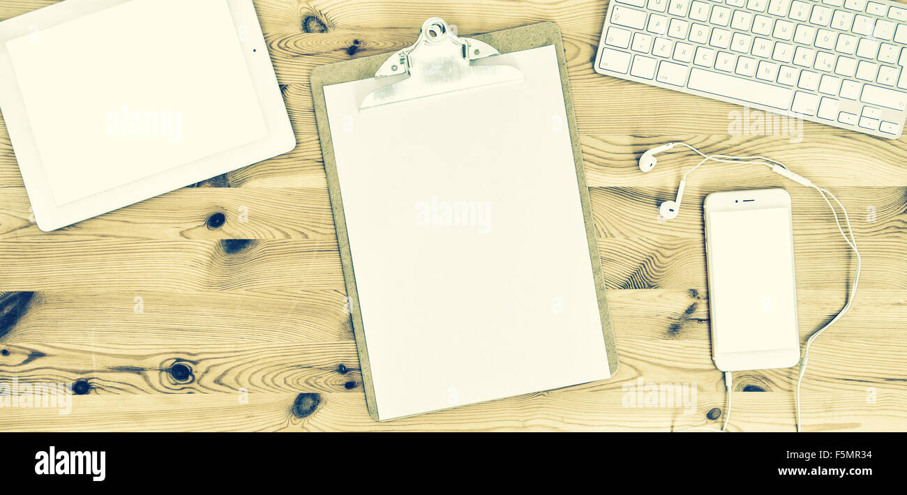 Travail de bureau avec des presse-papiers, papier, clavier, pavé tactile, le téléphone, un casque. Tons style vintage photo Banque D'Images