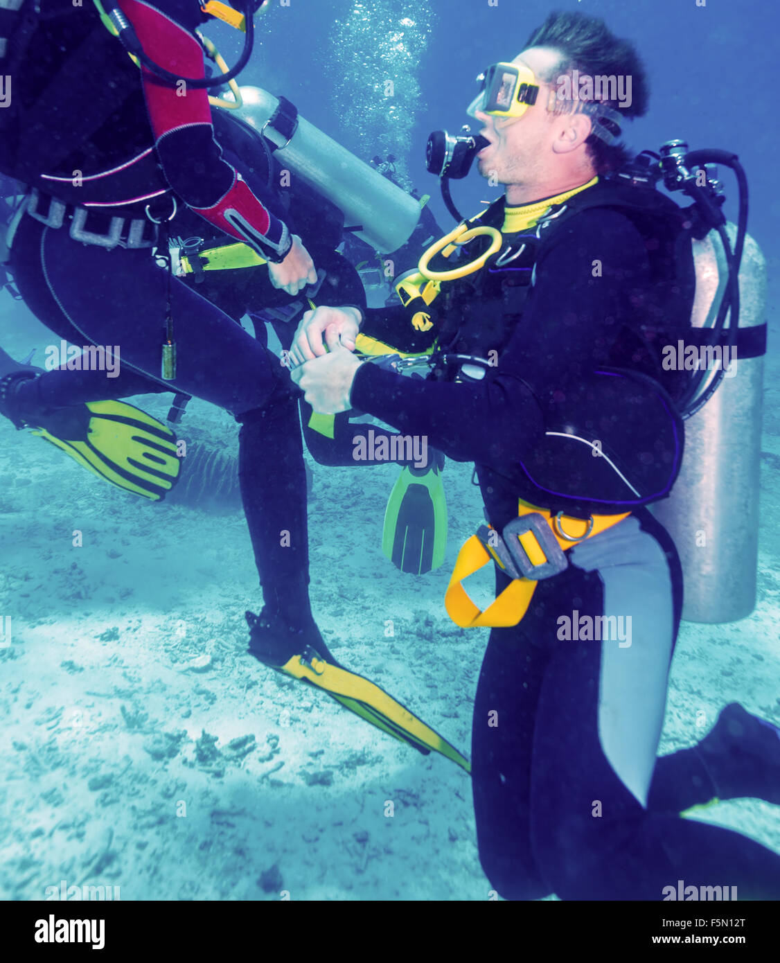 Jeune homme Scuba Diver de genou au fond de sable Banque D'Images