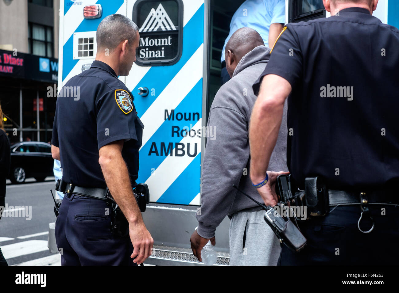 New York City, New York, USA. 11 novembre 2015 : aider un homme d'escorte de police dans une ambulance. Banque D'Images
