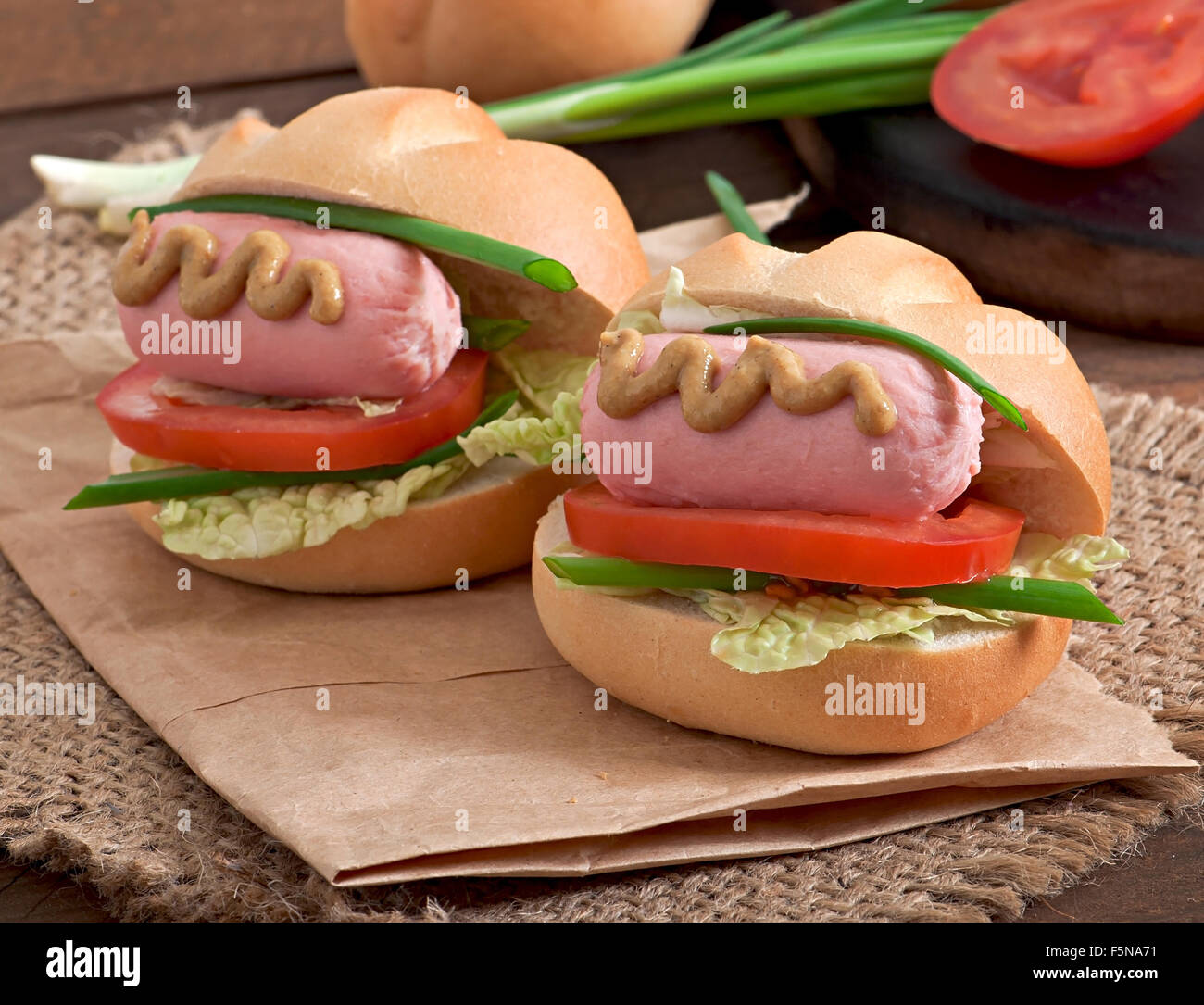 Peu joyeux hot dog avec de la saucisse et tomate Banque D'Images