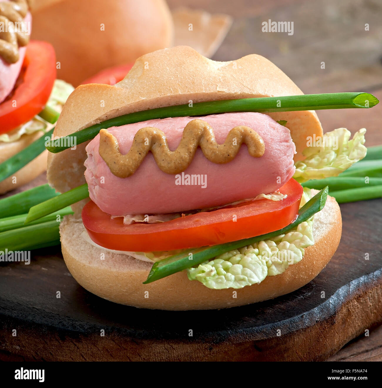 Peu joyeux hot dog avec de la saucisse et tomate Banque D'Images