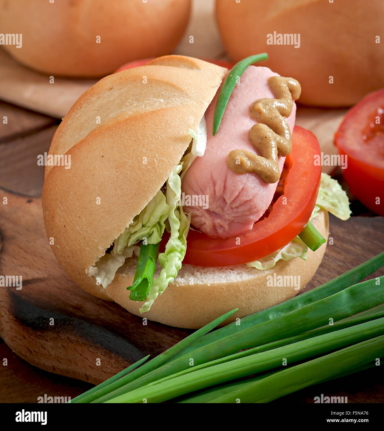 Peu joyeux hot dog avec de la saucisse et tomate Banque D'Images