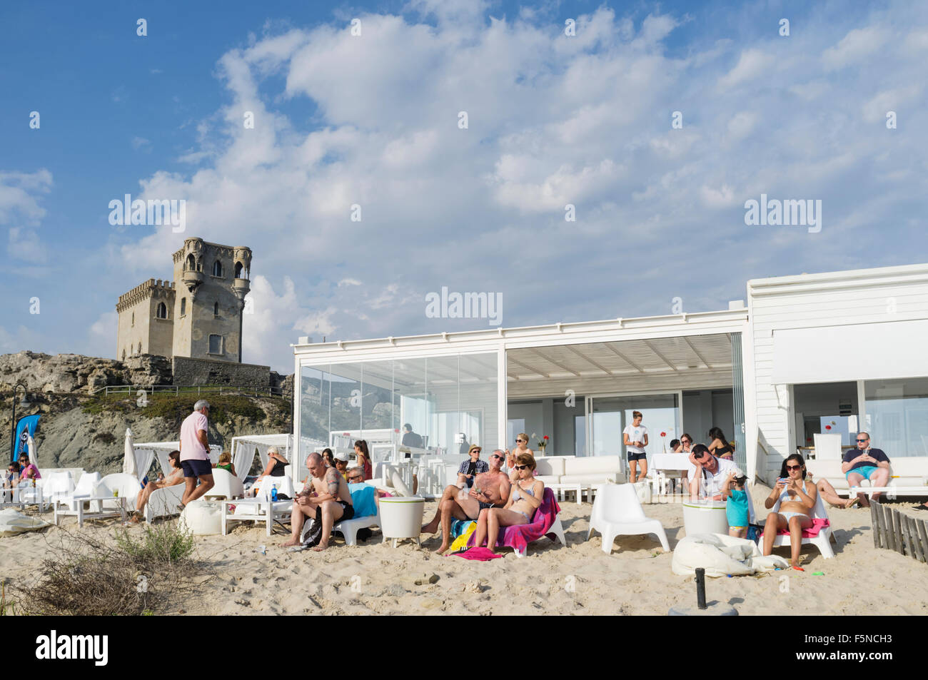 Les gens à un bar de plage en plein air avec château de Santa Catalina en arrière-plan. Tarifa, Cadiz Province, Andalusia, Spain Banque D'Images