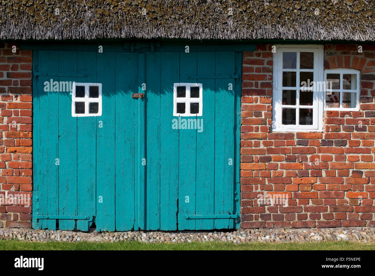 Portes de grange en bois sarcelle équilibre avec petites fenêtres toutes peintes avec du blanc des cadres. Il y a un petit drapeau danois dans la fenêtre. Banque D'Images