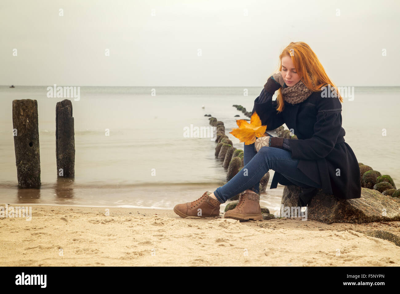 Triste pensive woman sur une plage de la mer d'automne assis, tonique libre Banque D'Images