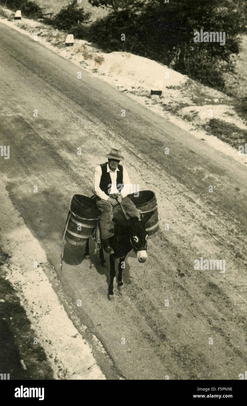 L'homme sur un âne transportant deux barils Banque D'Images
