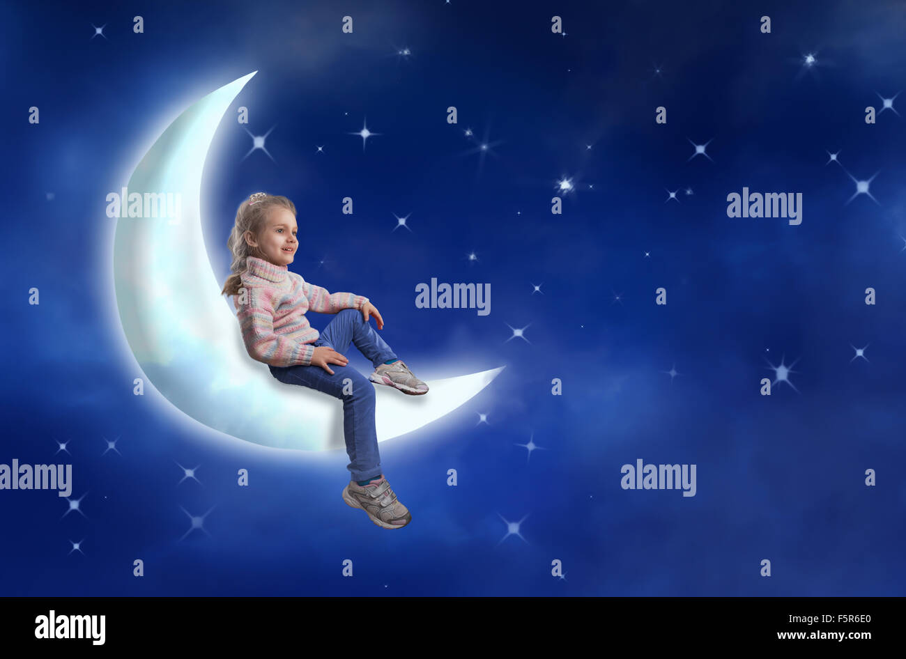 Belle petite fille est assise sur la lune contre ciel étoilé Banque D'Images