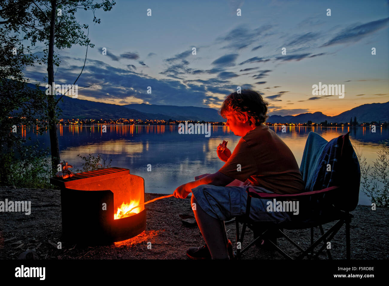 Garçon dans la guimauve rôtis au feu de camp camping Lakeshore, sẁiẁs Provincial Park, Osoyoos, Colombie-Britannique, Canada Banque D'Images