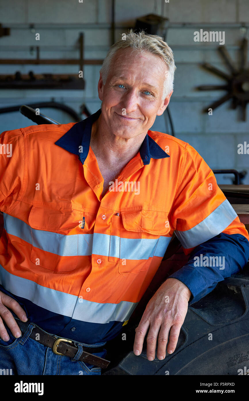Portrait d'un agriculteur de chiffons de sécurité à côté de son tracteur Banque D'Images