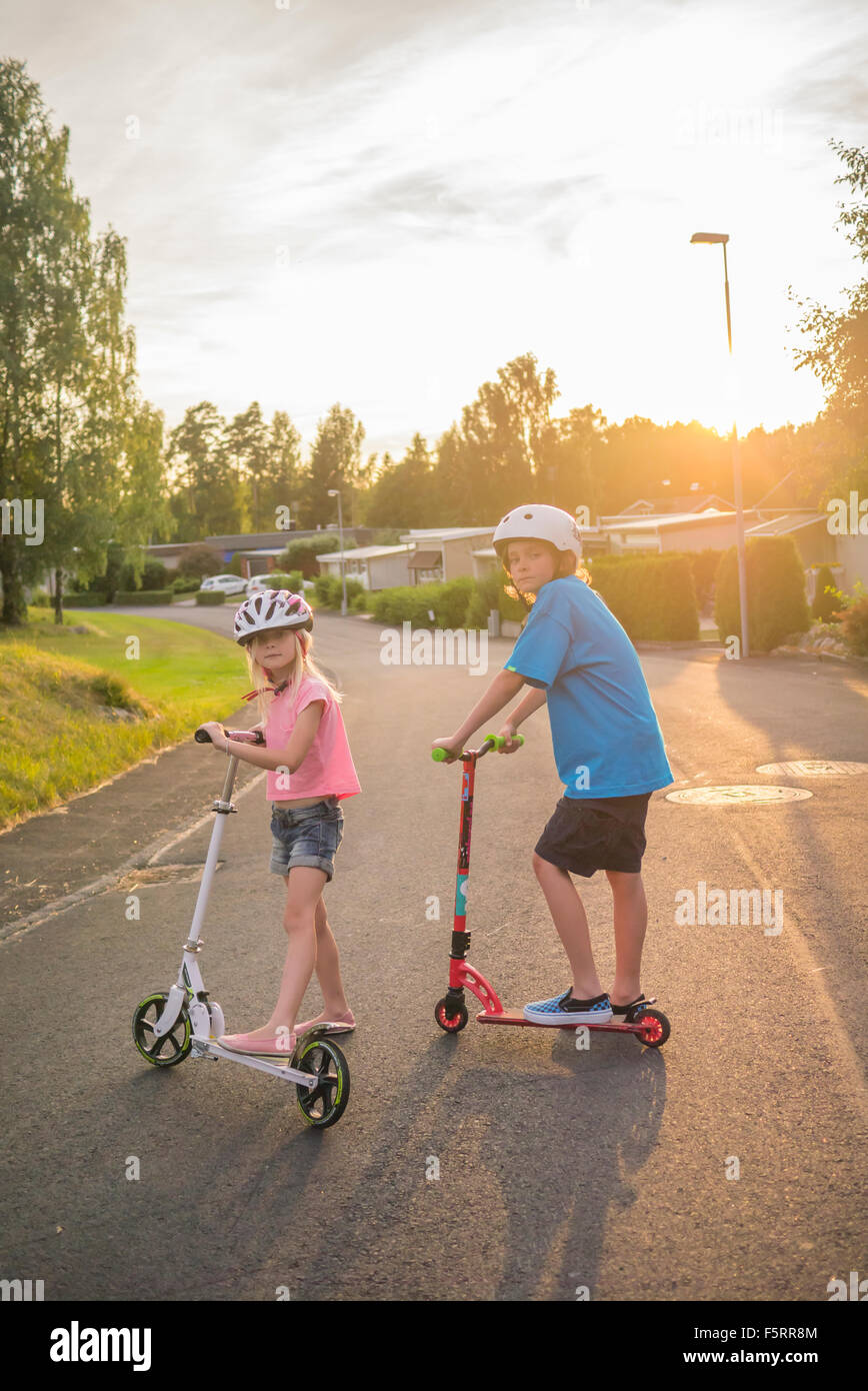 La Suède, Smaland, Bad Saulgau, Portrait of Girl (12-13) and boy (10-11) posant avec pousser des scooters en ville street Banque D'Images