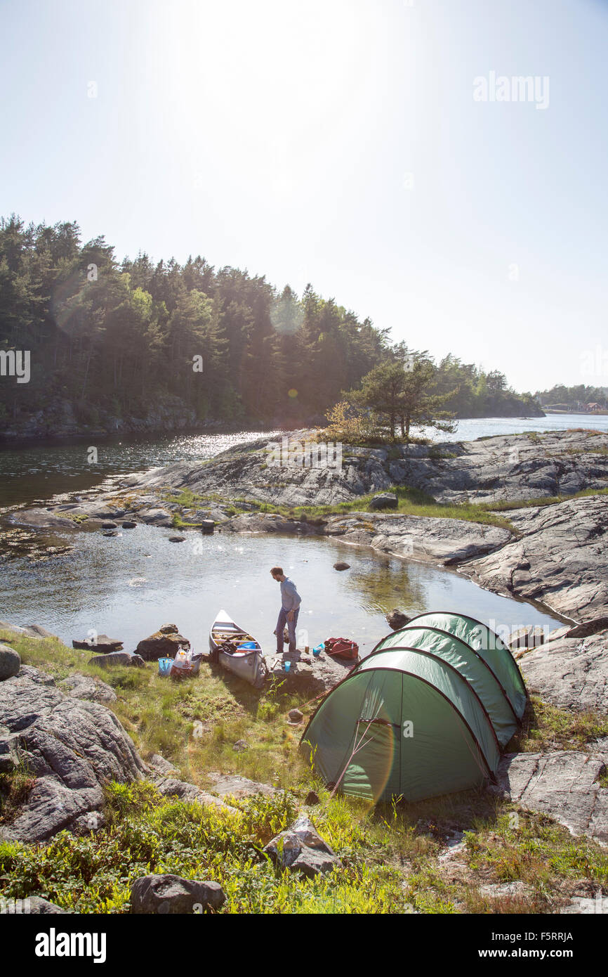 La Suède, côte ouest, Bohuslan, Flato, Man camping on riverbank Banque D'Images