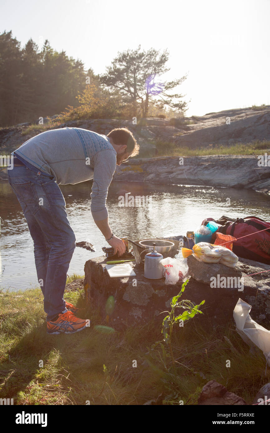 La Suède, côte ouest, Bohuslan, Flato, Man camping on riverbank Banque D'Images