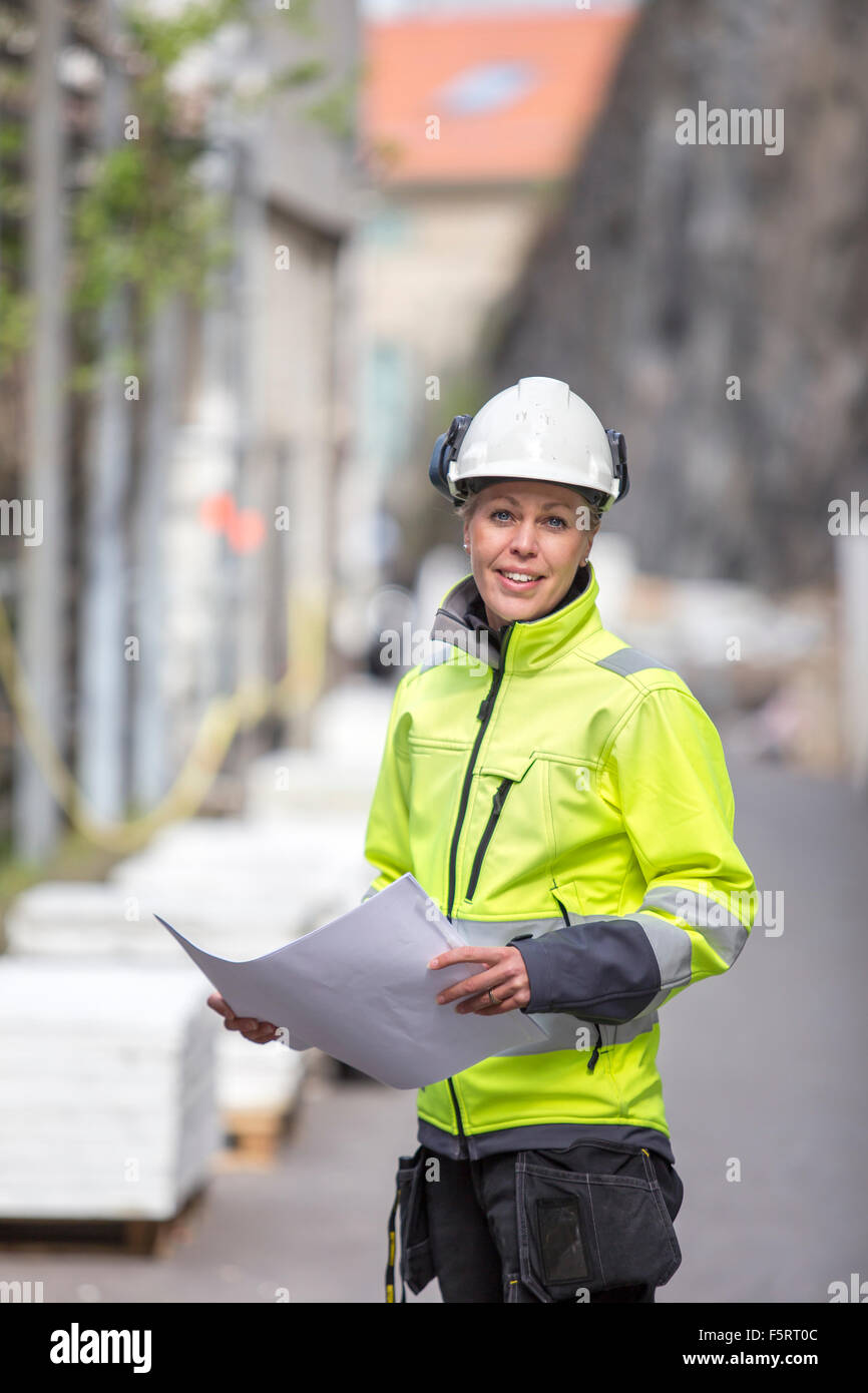 La Suède, Vastergotland, Smiley construction worker with blueprints Banque D'Images
