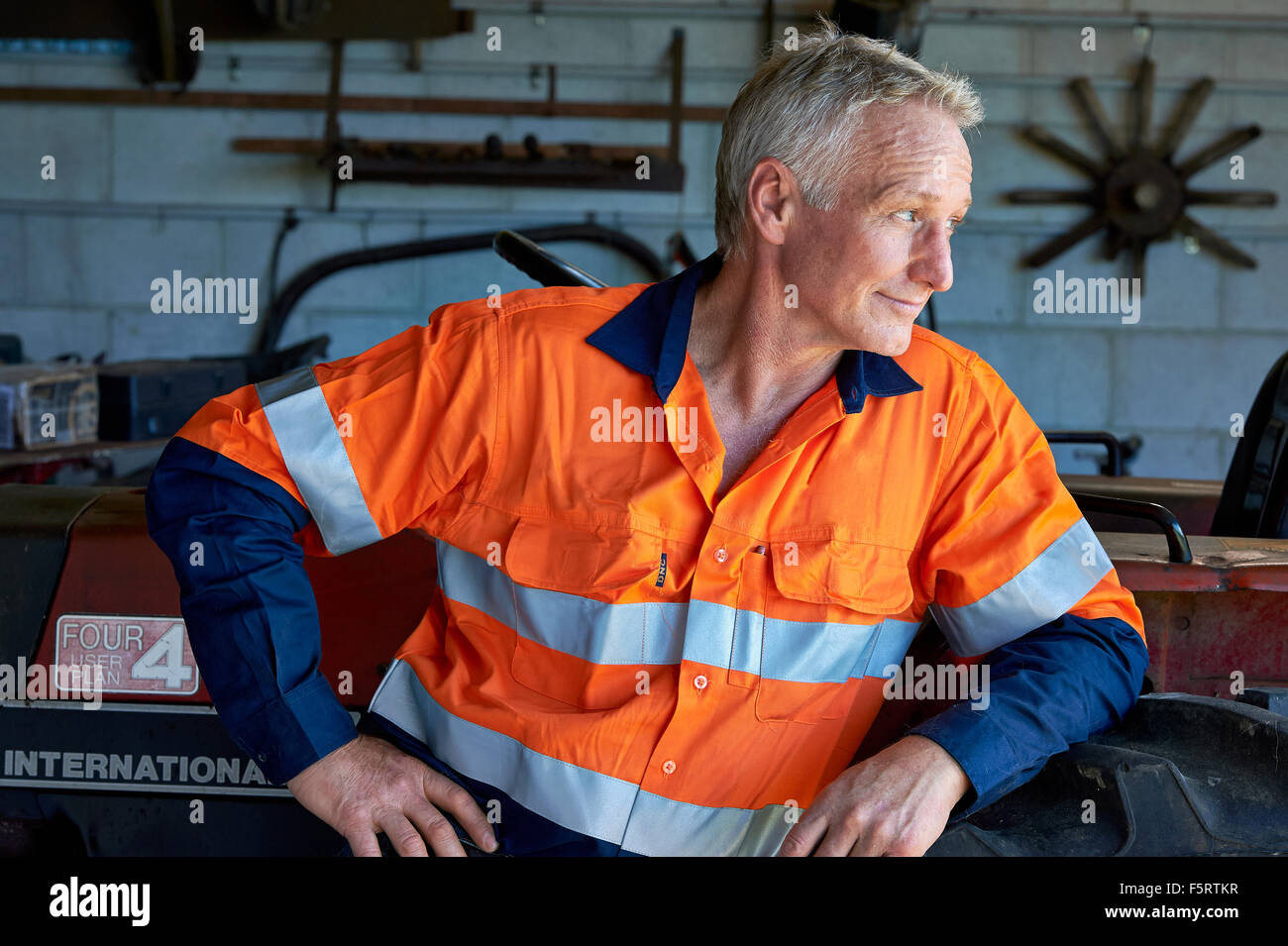 Agriculteur dans son hangar à côté de son tracteur Banque D'Images