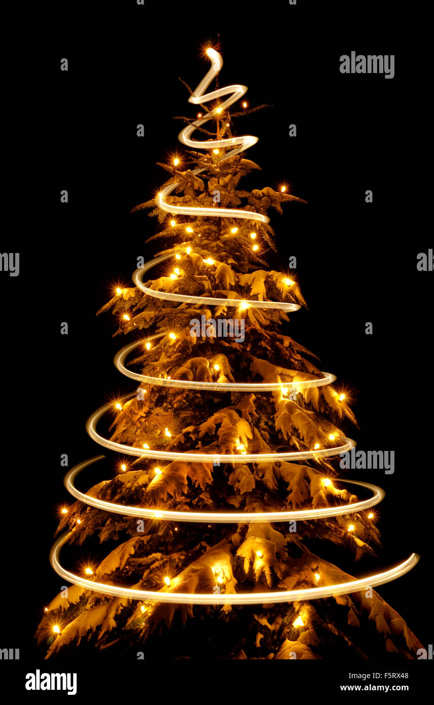 Arbre de Noël étincelante avec une spirale de lumière, comme par magie, tracé autour d'elle, isolé sur fond noir Banque D'Images
