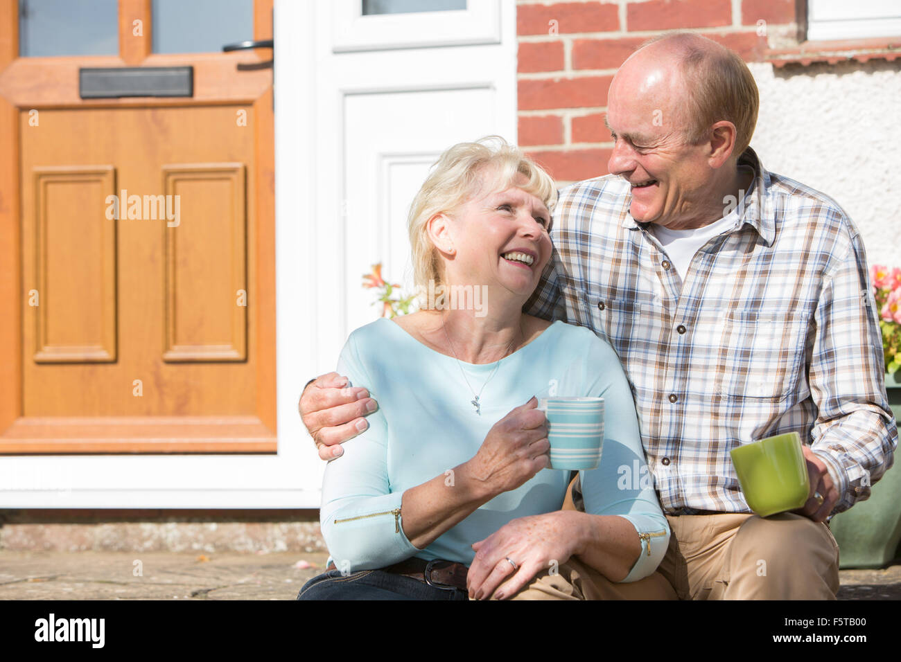 Senior Couple Sitting Outside House avec tasse de café Banque D'Images