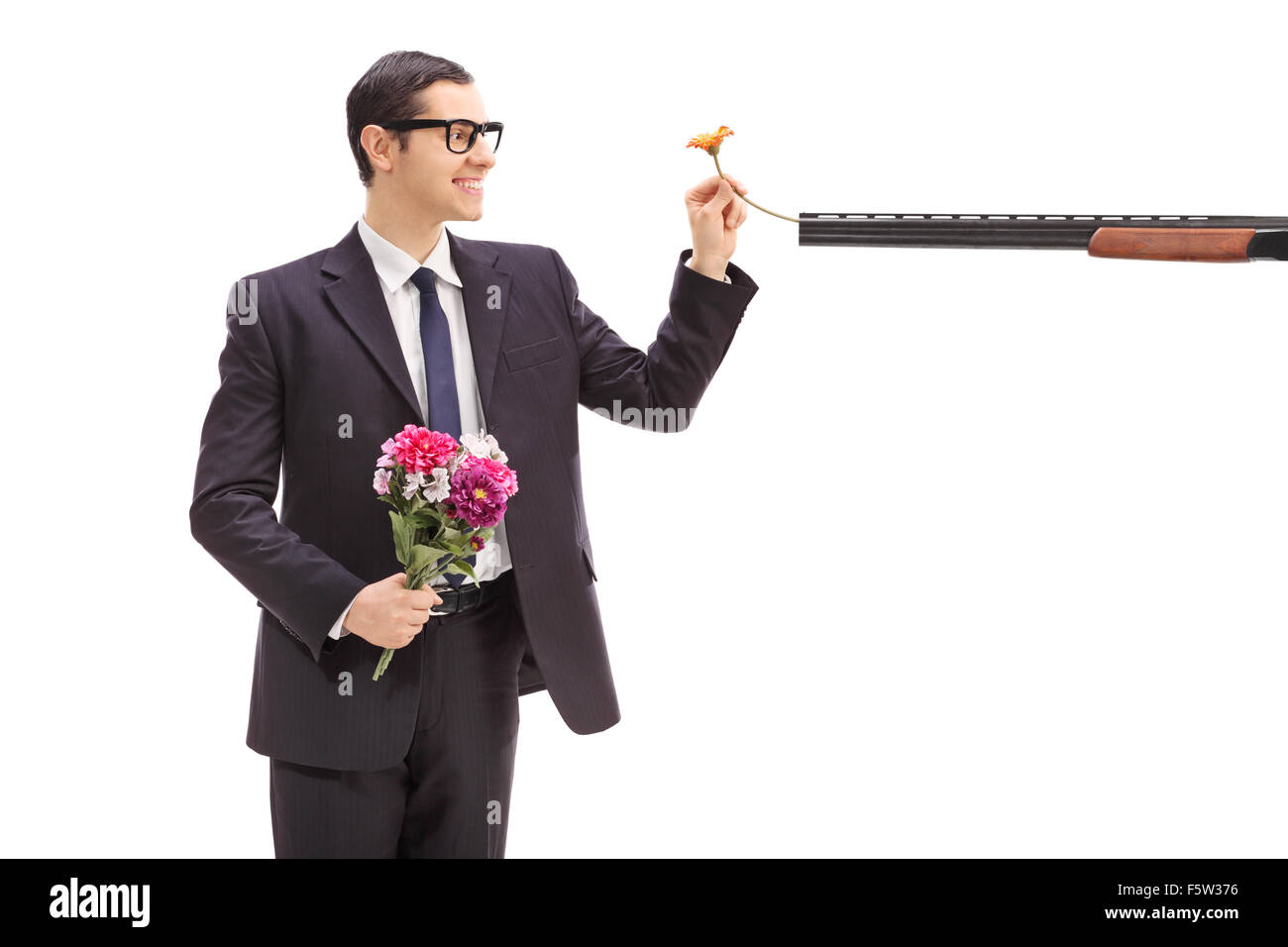 Joyful businesswoman holding a bouquet de fleurs et de mettre une fleur dans un fusil pointé sur lui Banque D'Images