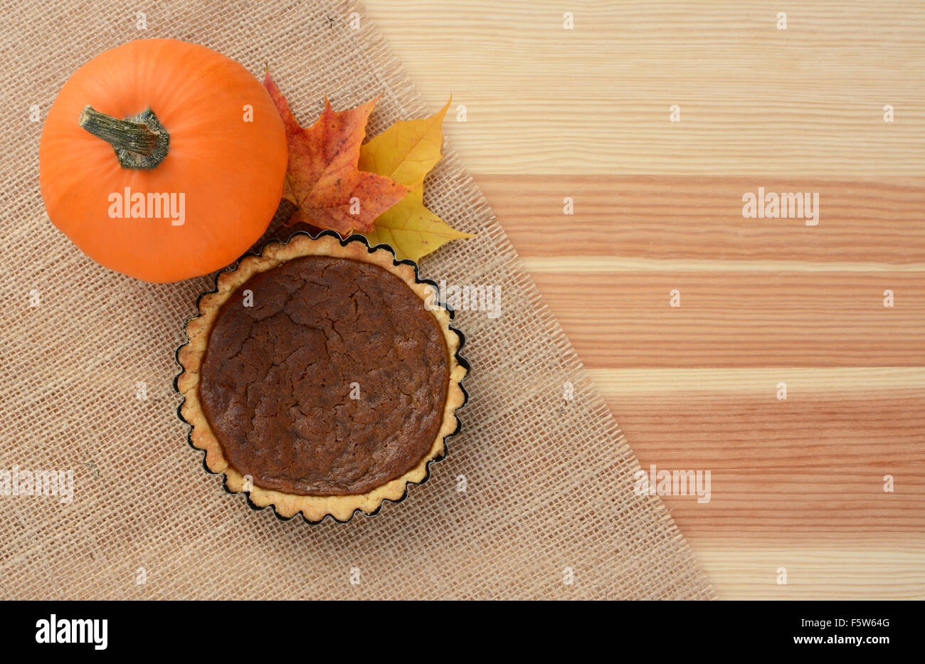 Potiron Sucre et mini tarte à la citrouille avec l'automne feuilles d'érable sur le bois et de Hesse, with copy space Banque D'Images