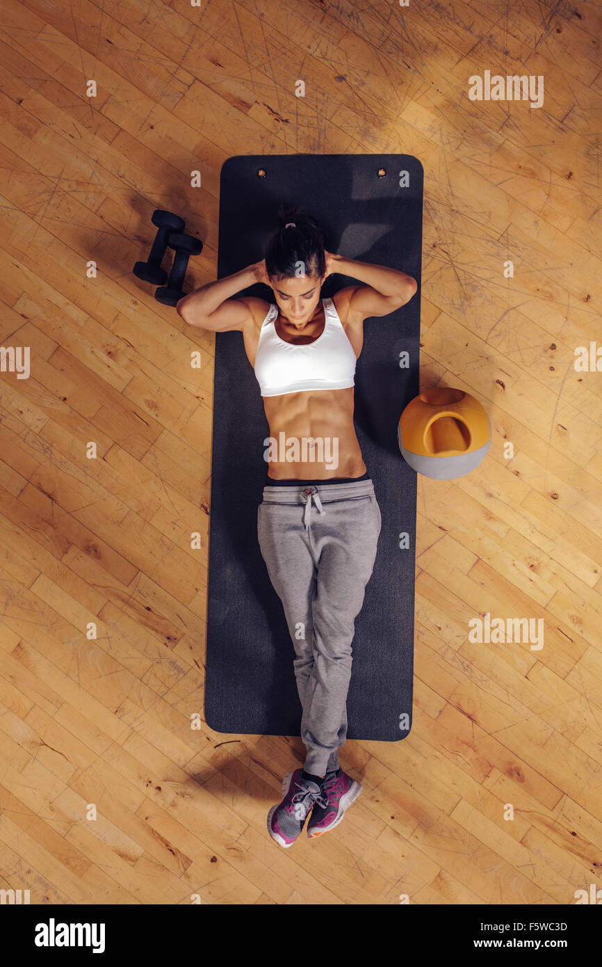 Fit young woman lying on exercise mat faisant des exercices de l'estomac. Vue aérienne de femmes à la salle de sport Banque D'Images