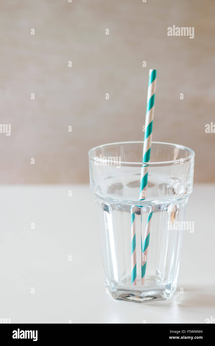 Verre à cocktail vide avec retro cocktail rayé blanc tube sur table. La lumière naturelle du jour Banque D'Images