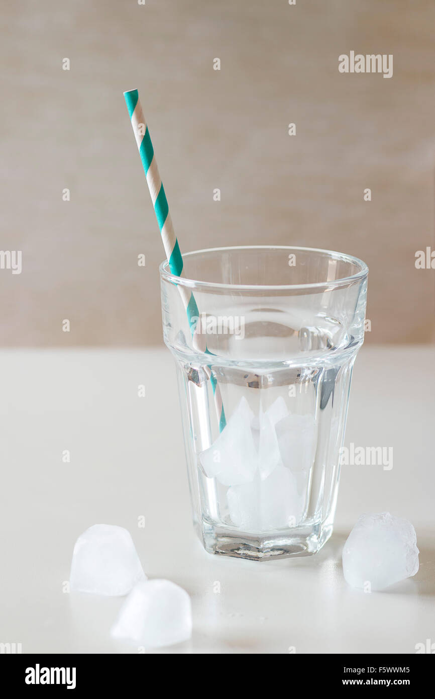 Vide verre à cocktail avec des glaçons et le bar à cocktails rétro le tube sur la table blanche. La lumière naturelle du jour Banque D'Images