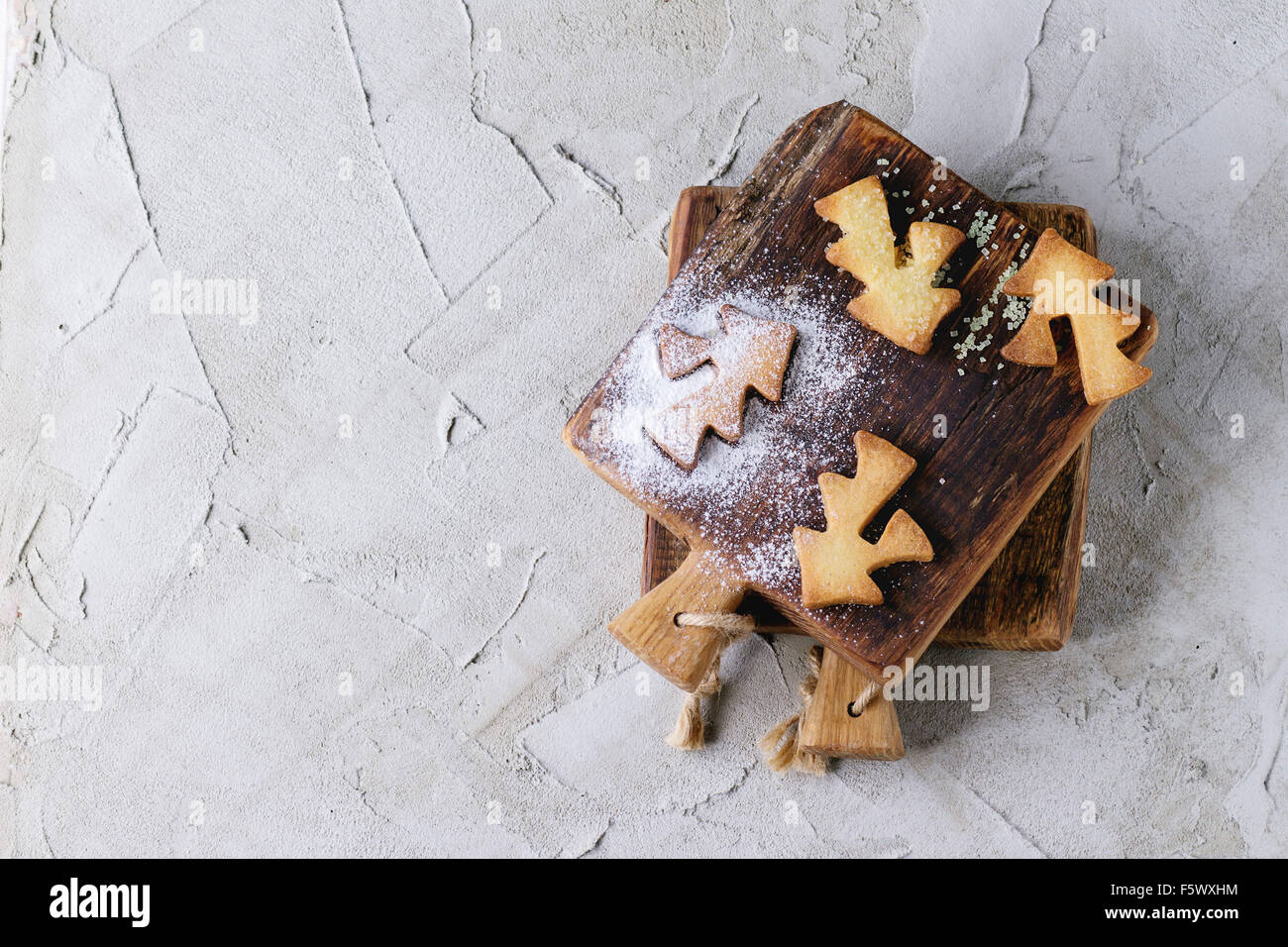 Shortbread cookies de Noël pour les tasses de sucre en poudre sur petite planche à découper en bois gris sur surface plâtrée. Formes Cookies Banque D'Images