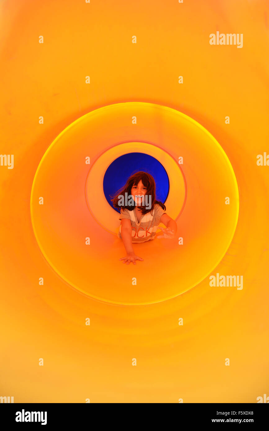 Une petite fille faisant glisser à l'intérieur d'une diapositive d'orange. Banque D'Images