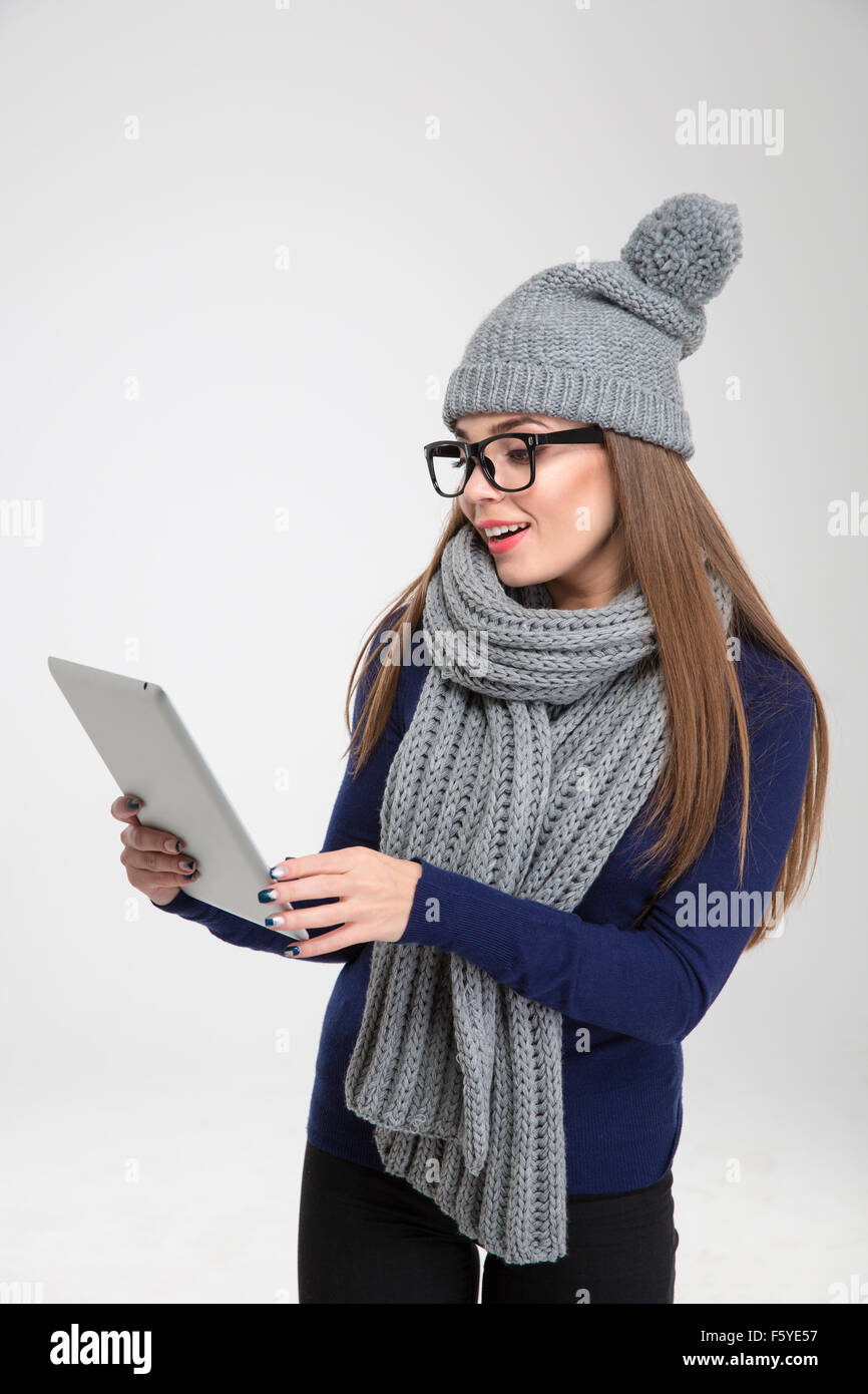 Portrait d'une jeune femme en tissu d'hiver using tablet computer isolé sur fond blanc Banque D'Images