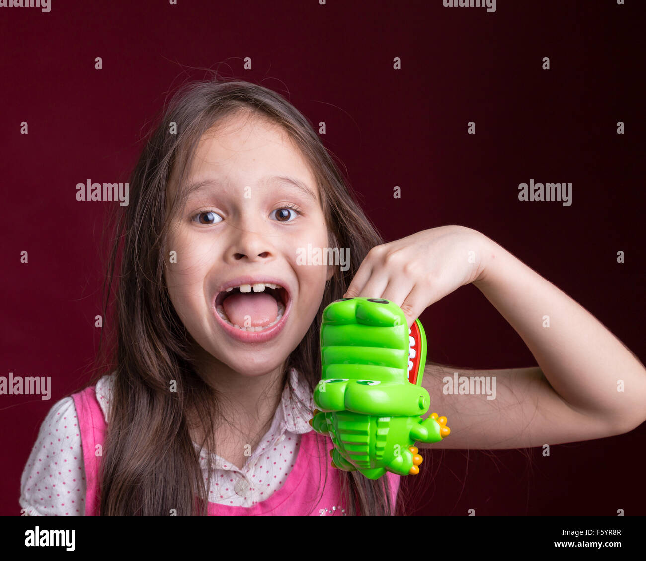 Young Asian American Girl with toy crocodile vert main piqueurs Banque D'Images