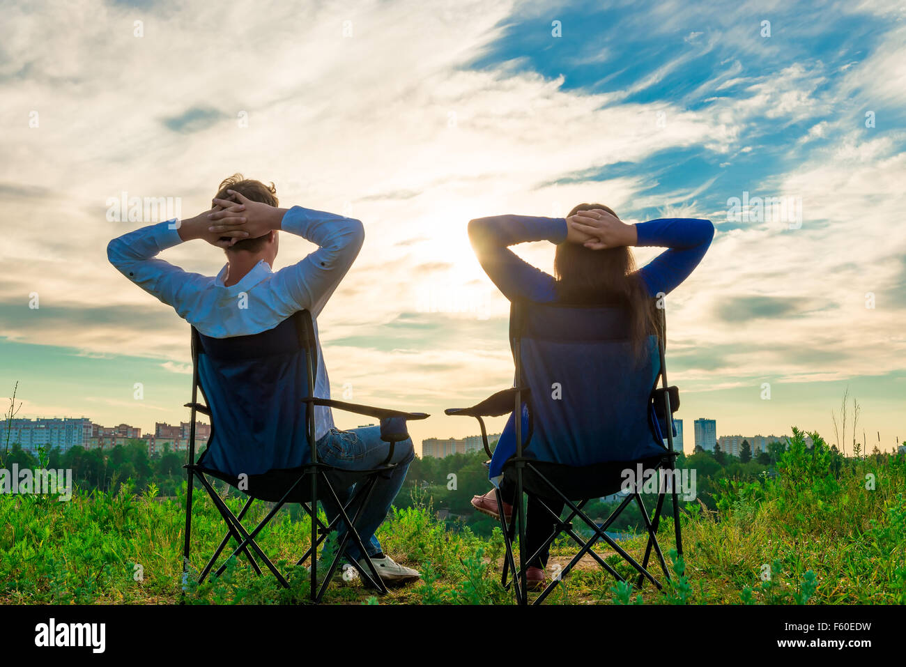 Couple assis dans des chaises et admirer le lever du soleil sur la ville Banque D'Images