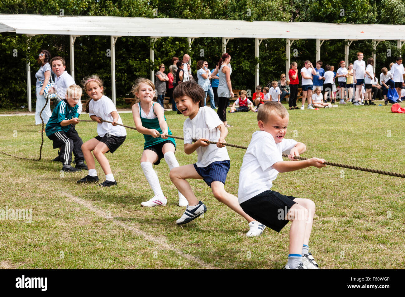 Les enfants, 7-9 ans. À l'extérieur à l'école une journée du sport. À la corde, de l'équipe pieds creusés dans, avec l'équipe de g enfants tendant la corde de traction. Banque D'Images