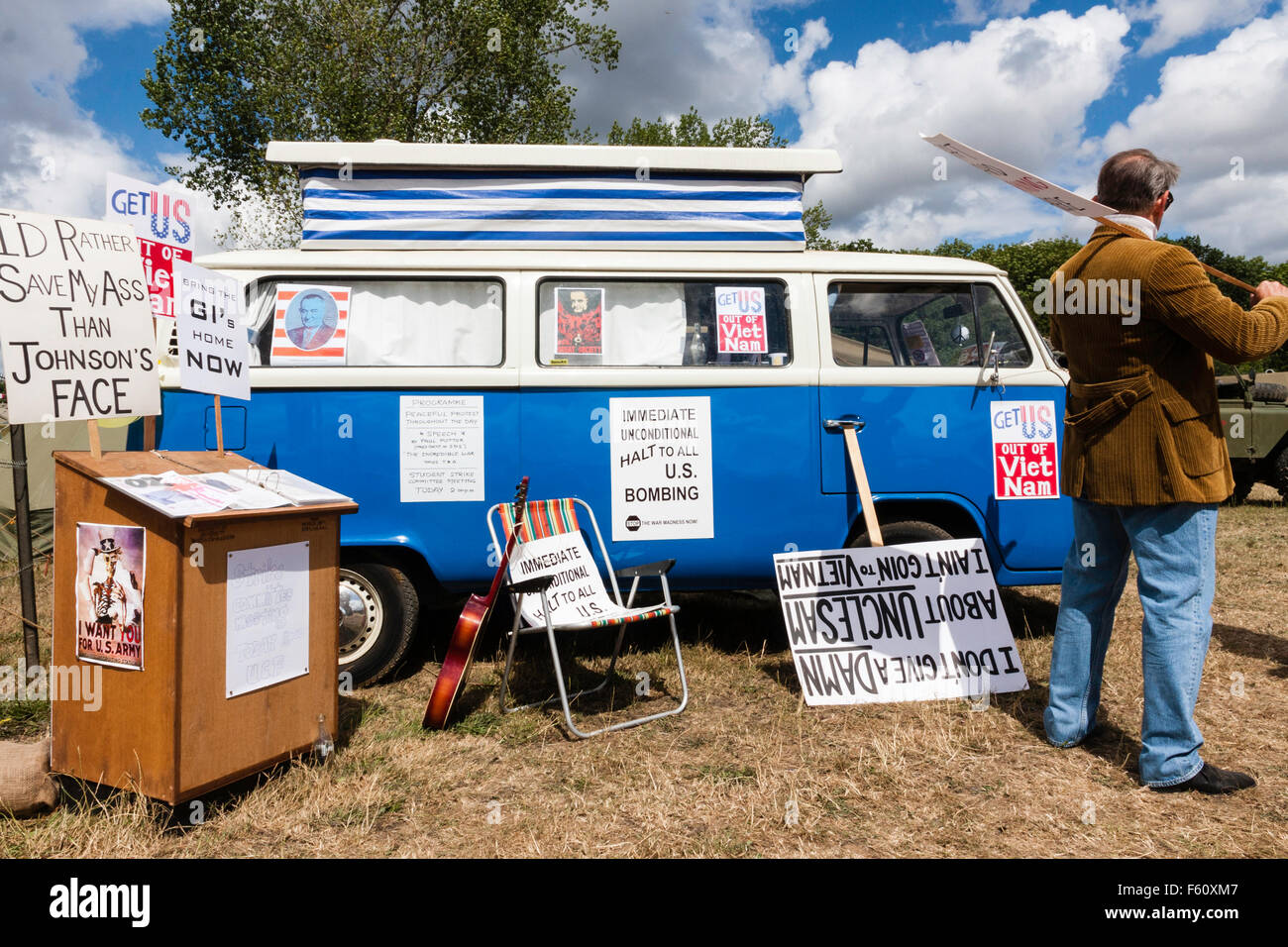 Reconstitution de la guerre du Vietnam. Les manifestant anti-guerre se tient en dehors de son VW camper van, avec diverses plaques calé contre van. Banque D'Images