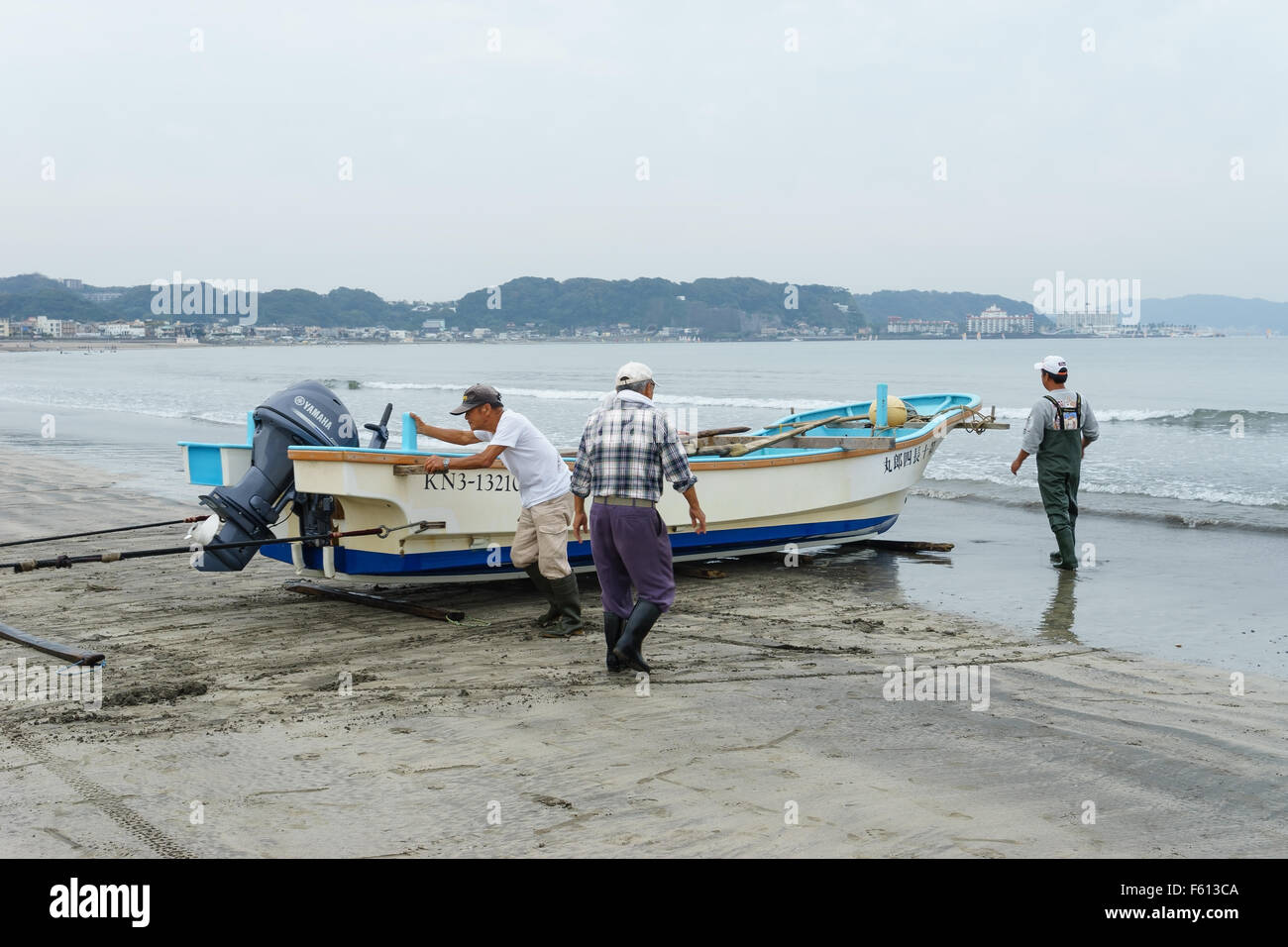 Les pêcheurs haler un voile de la mer à la plage à Kamakura, au Japon. Banque D'Images