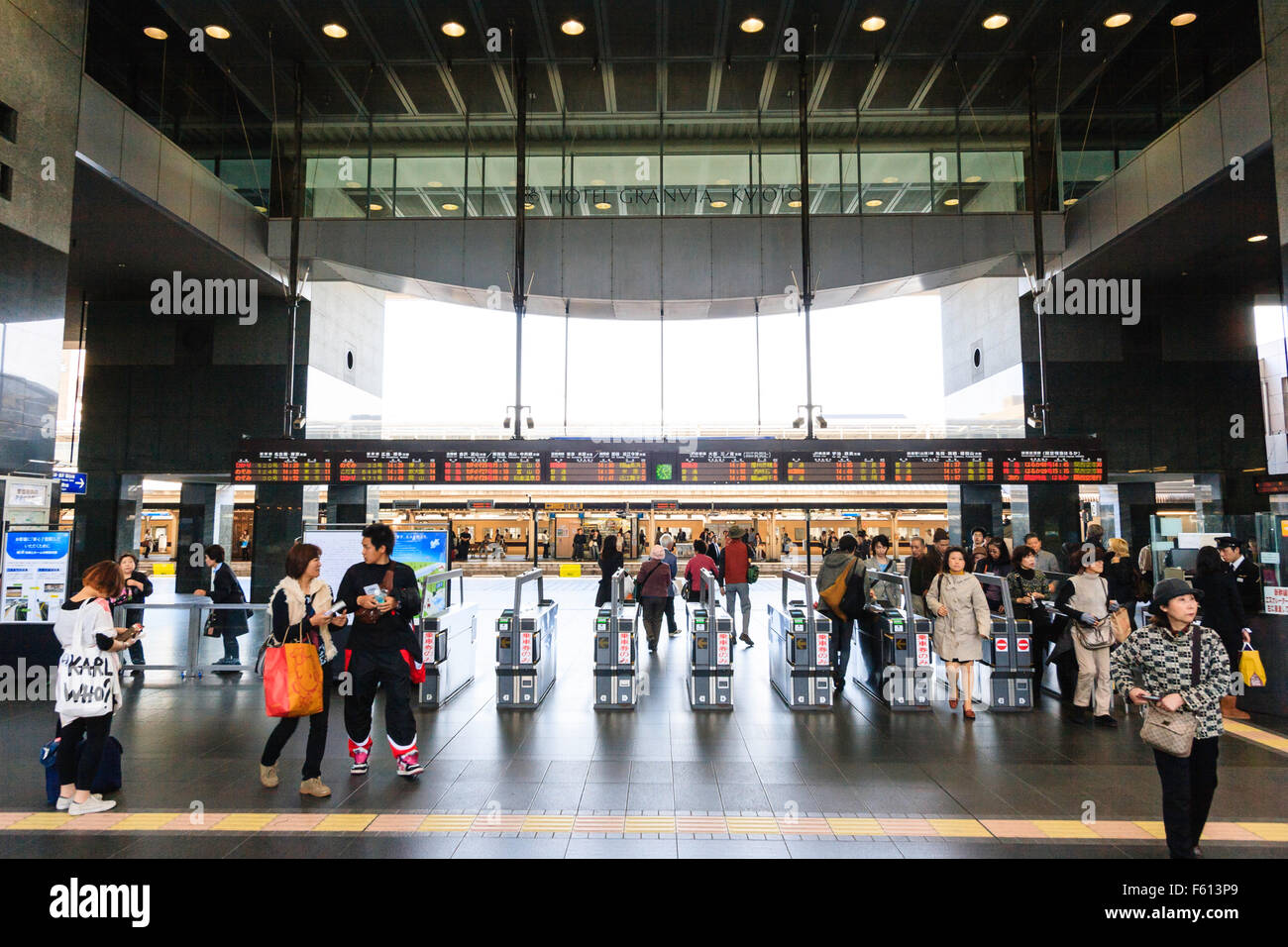 Intérieur de la gare de Kyoto. Ticket principal barrière avec les gens qui viennent à travers des barrières automatiques à partir de plates-formes. Au-dessus d'eux, ligne de train d'info s'affiche. Banque D'Images