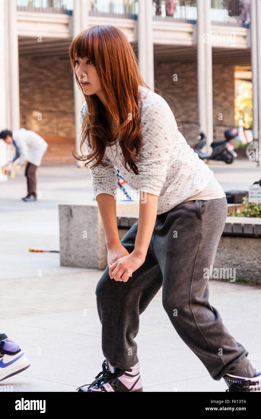 Le Japon, Nishinomiya. Close up, teenage girl laughing japonais assez mince et pratiquer la danse de la place déserte Banque D'Images