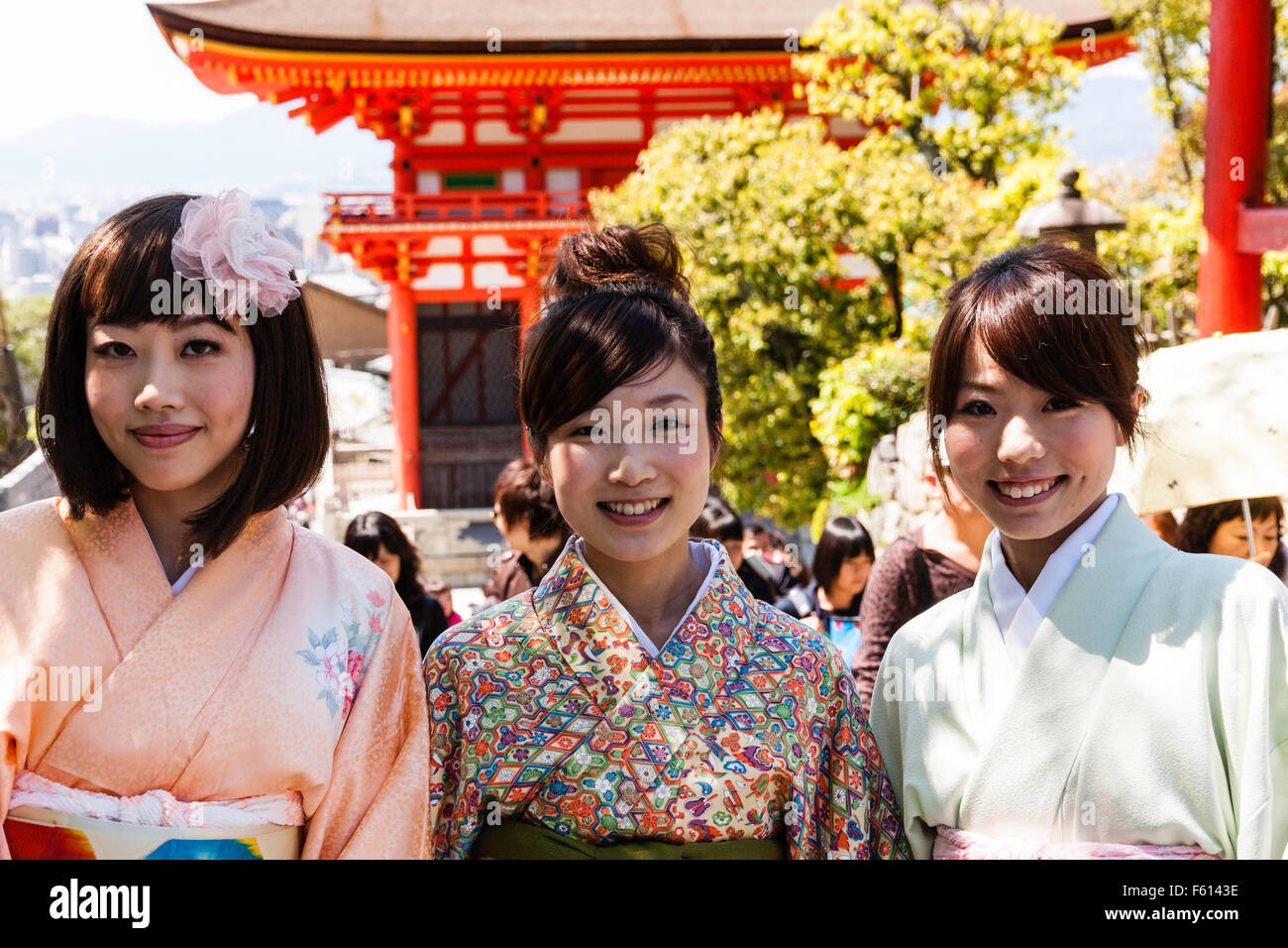 Le Japon, Kyoto, temple Kiyomizu dera. Trois jeunes femmes japonaises en kimono, smiling at viewer avec le Deva Gate derrière eux. Tourné la tête et des épaules. Banque D'Images