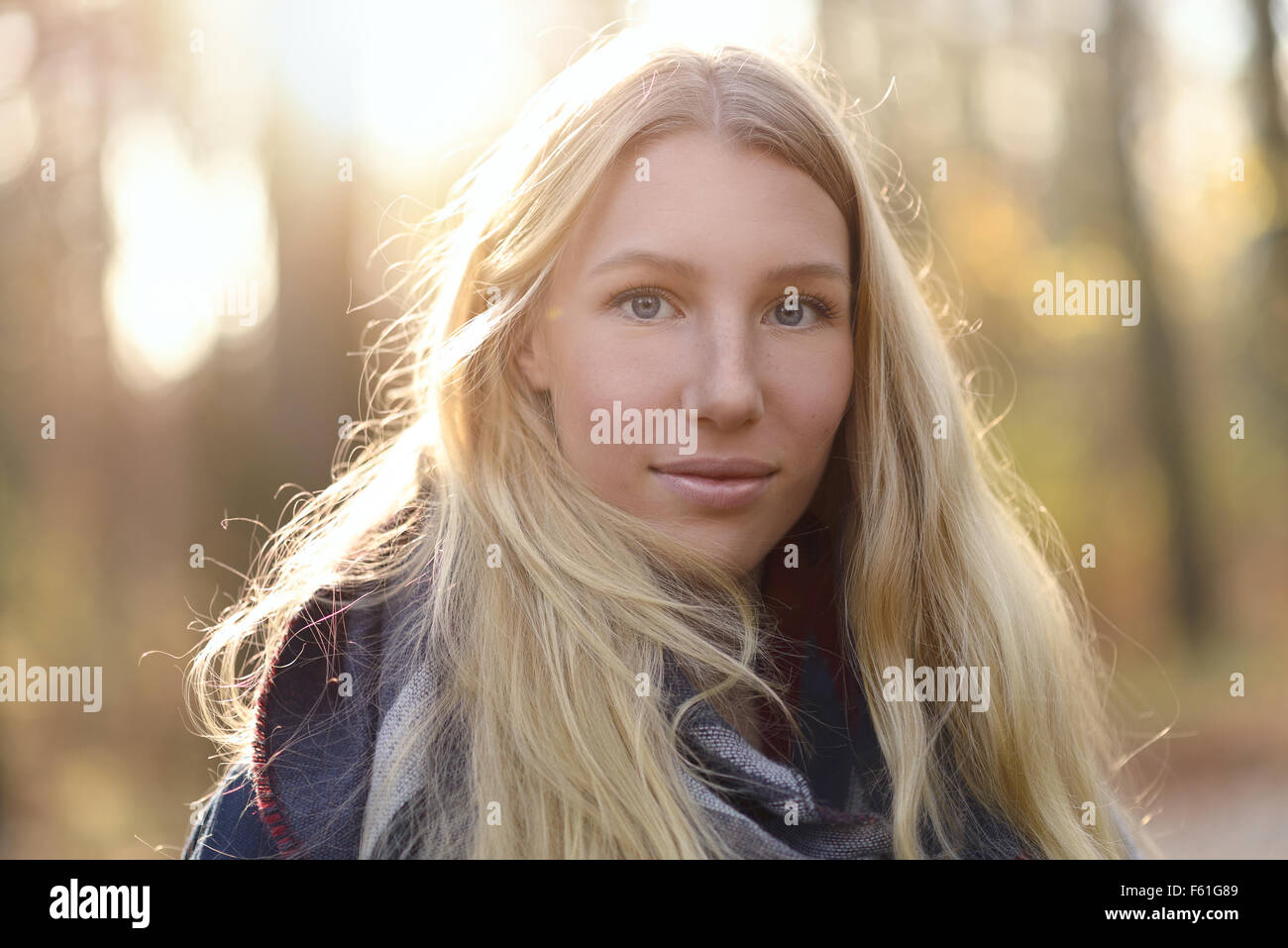 Jolie jeune femme avec de longs cheveux blonds en automne fashion portant un foulard à la mode standing outdoors smiling forestiers à l'automne Banque D'Images