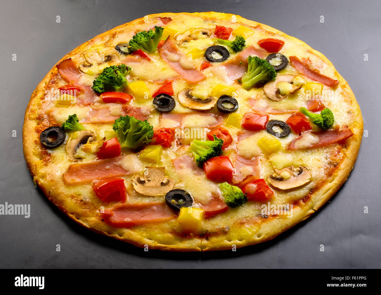 La pizza sur un fond sombre avec du jambon, champignons, chou-fleur, olives, fromage et piment doux Banque D'Images