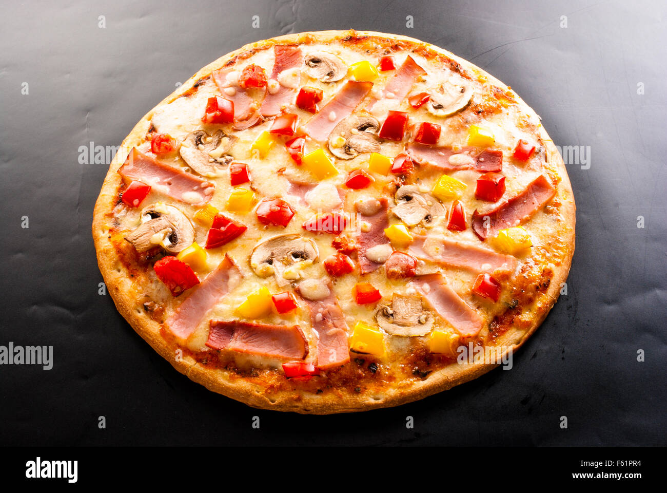 La pizza sur un fond sombre avec du jambon, champignons, chou-fleur, olives, fromage et piment doux Banque D'Images