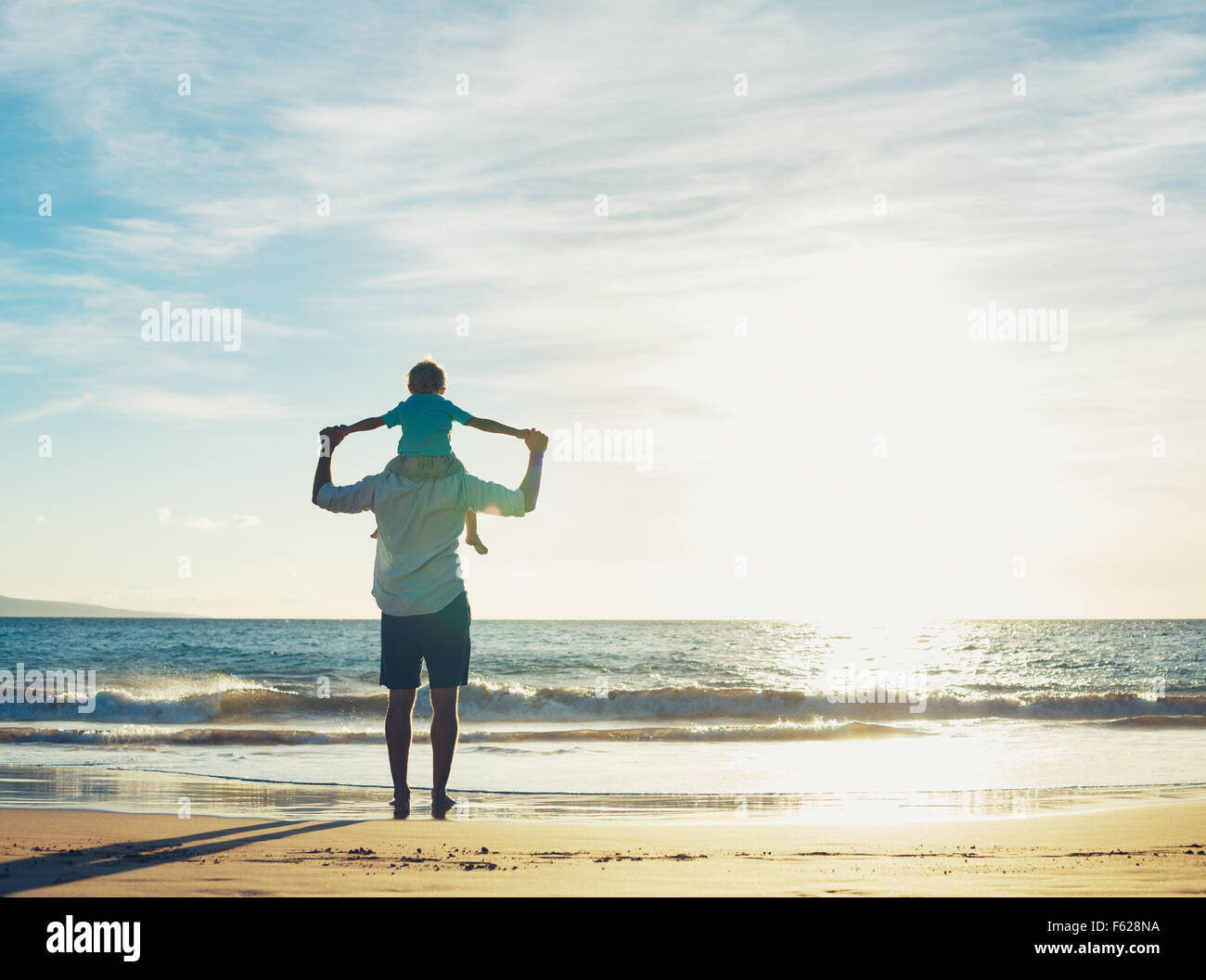 Père et fils jouant sur la plage au coucher du soleil, la qualité du temps en famille. Banque D'Images