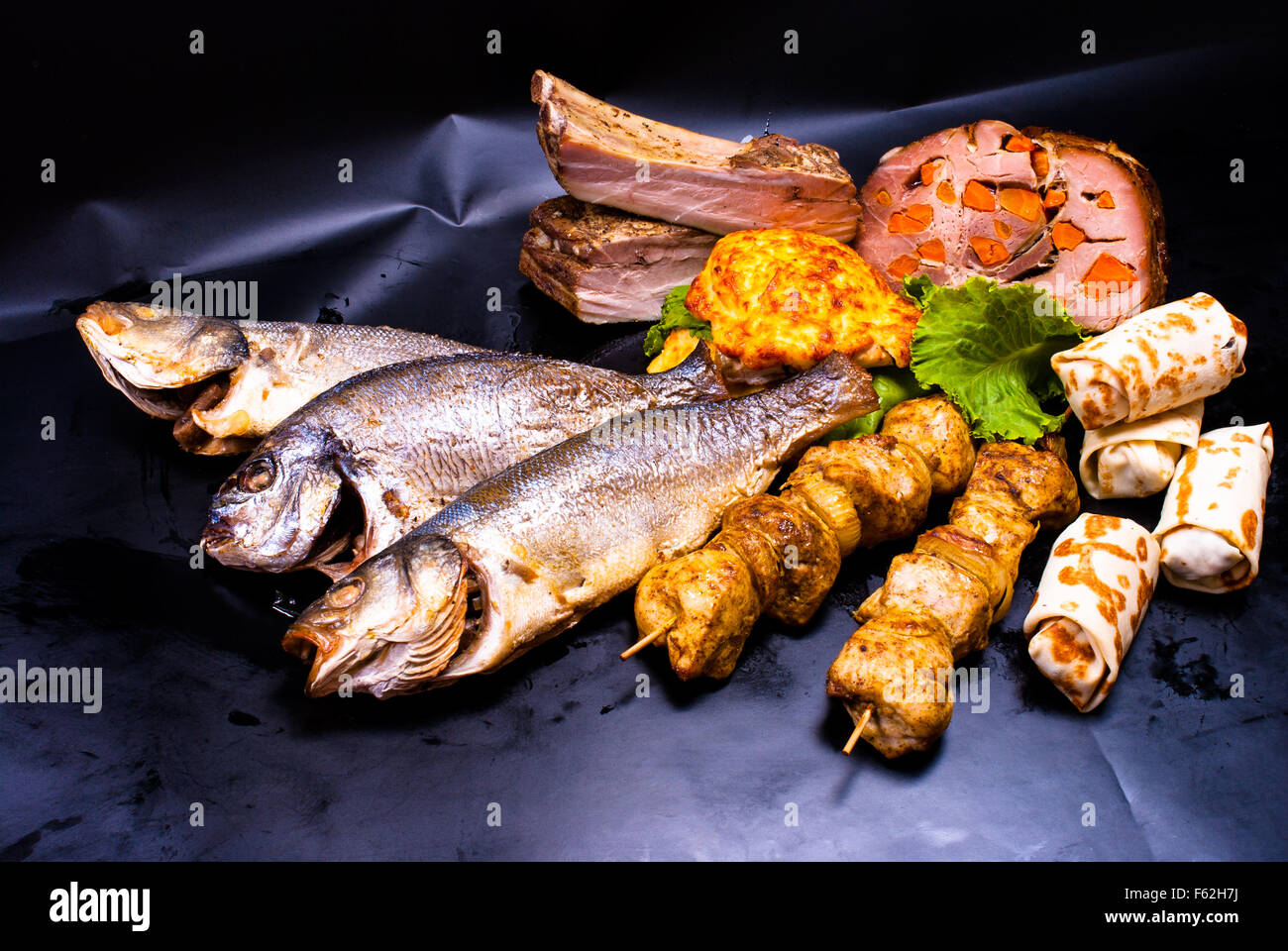 Still Life - avec la viande farcie, shish kebab, steak en pâte à crêpes, avec des remplissages, friture de poissons sur le fond noir Banque D'Images