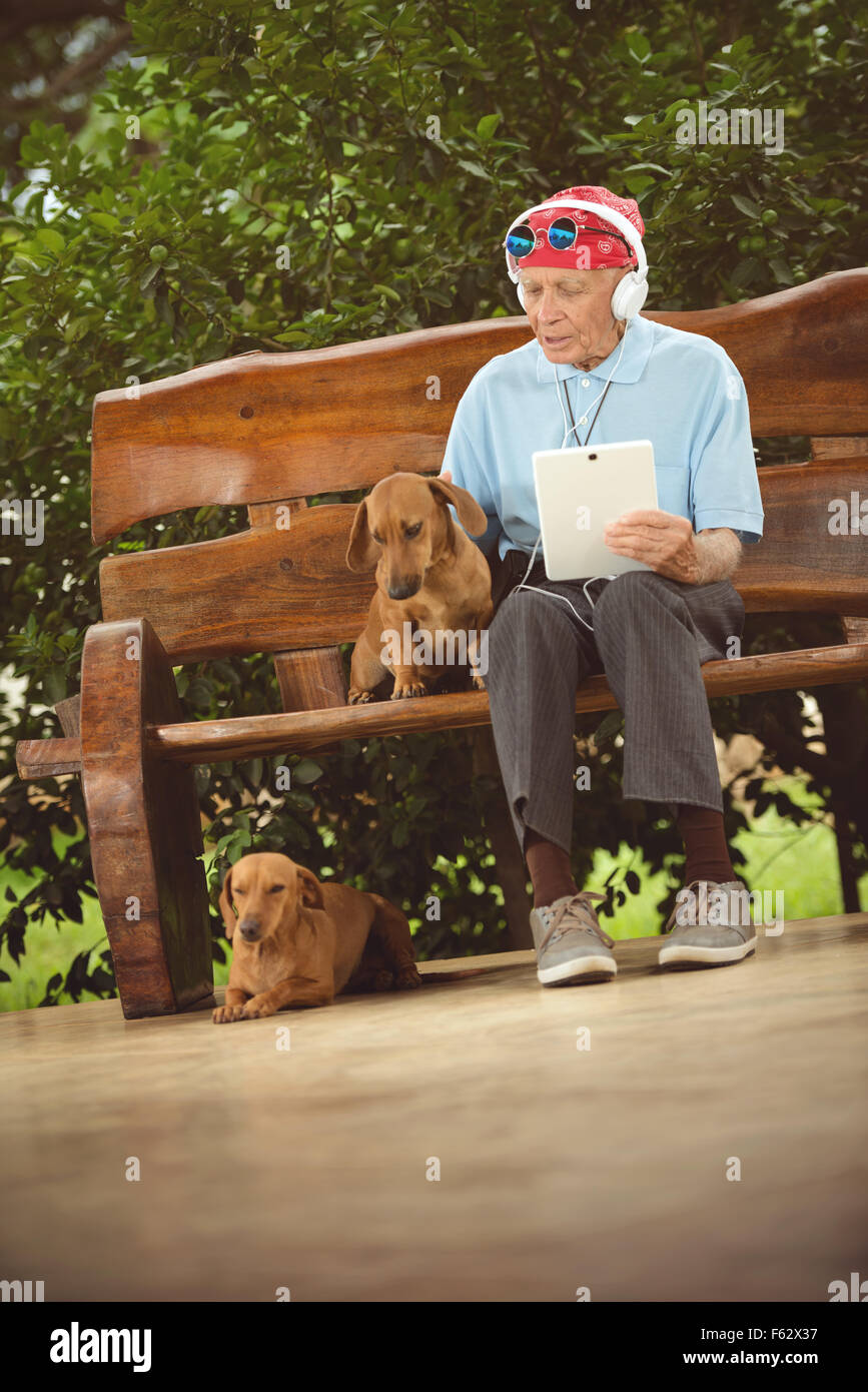 Un homme âgé avec bandana, lunettes et casque d'écoute, rock and roll sur la tablette. Banque D'Images