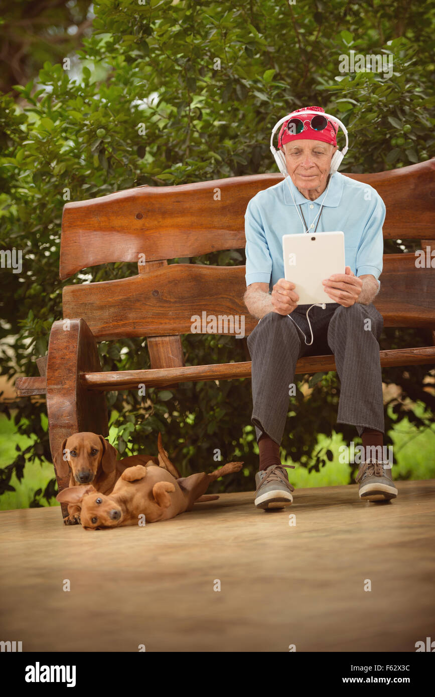 Un homme âgé avec bandana, lunettes et casque d'écoute, rock and roll sur la tablette. Banque D'Images