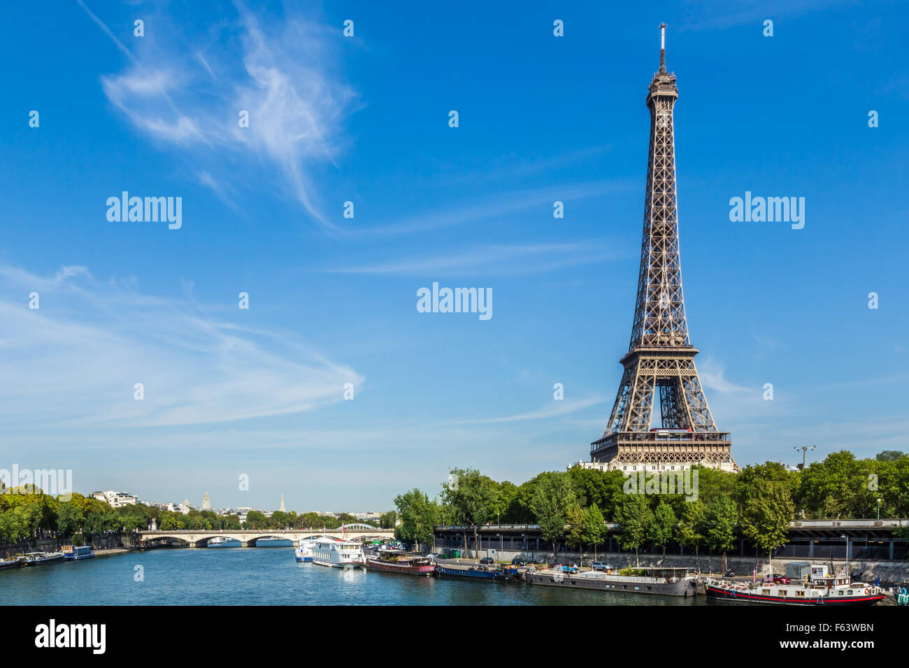 La Tour Eiffel contre un ciel bleu, avec des nuages filandreux. Au premier plan sont des bateaux sur la Seine. Banque D'Images