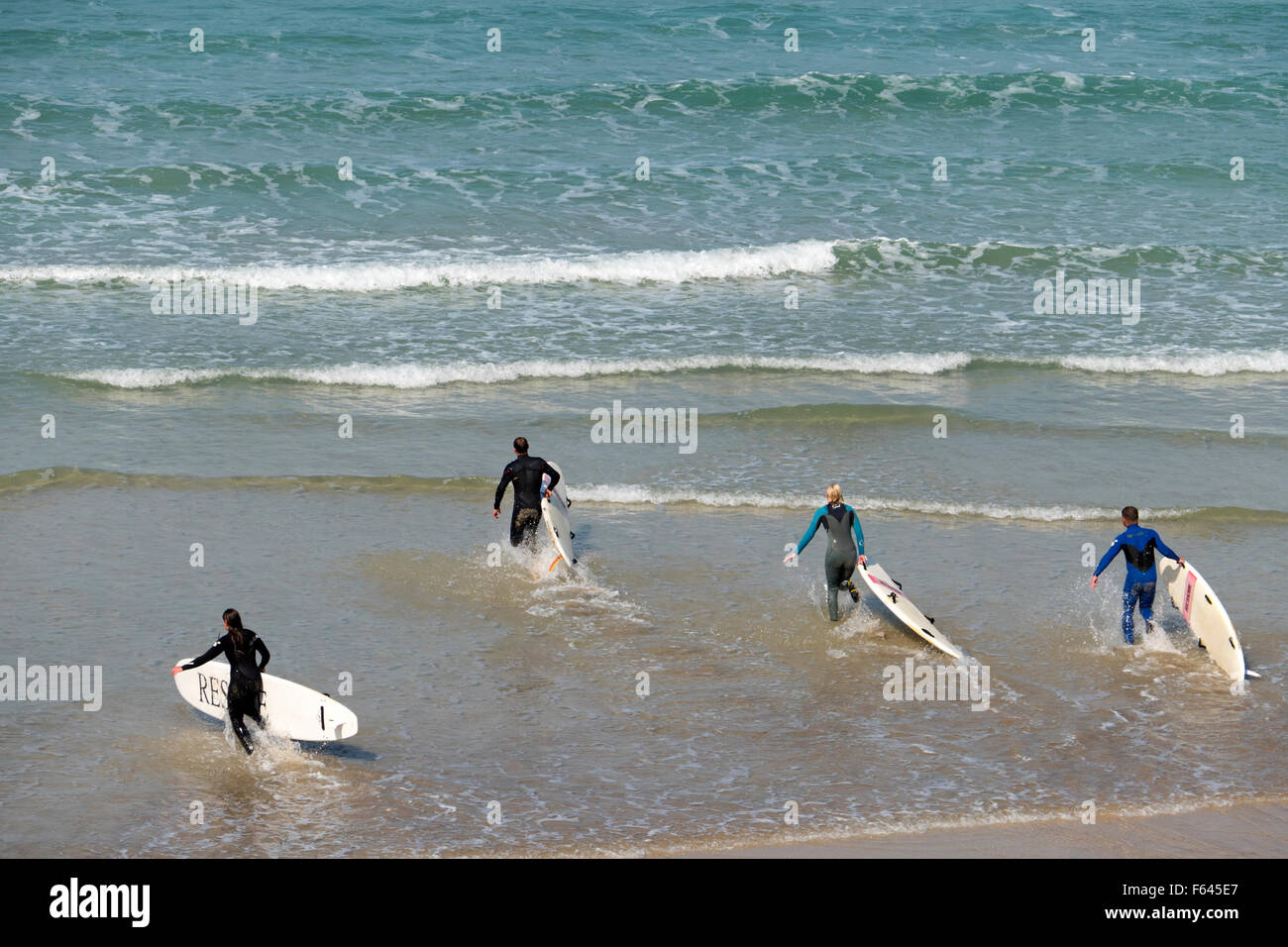 Dans l'exécution de surfeurs à la mer à Newquay, Cornwall, Angleterre. Banque D'Images